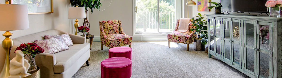 Living room with pink and floral decor with a view of a balcony